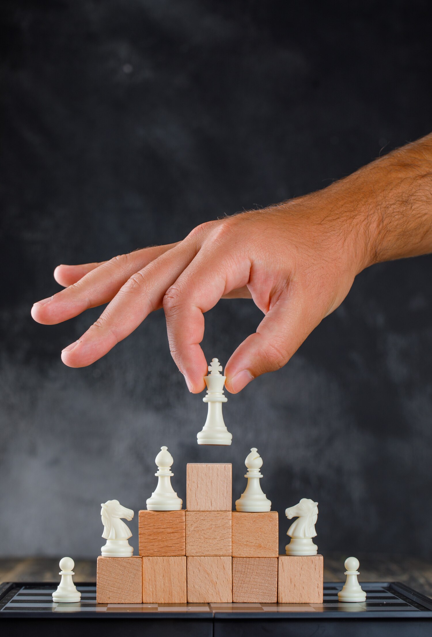 business-success-concept-with-chessboard-side-view-man-placing-figure-pyramid-blocks_176474-9274